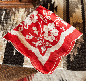 Red handkerchief with white floral pattern on a textured surface